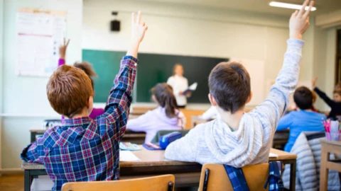 Niños sentados en un pupitre particpando en clase