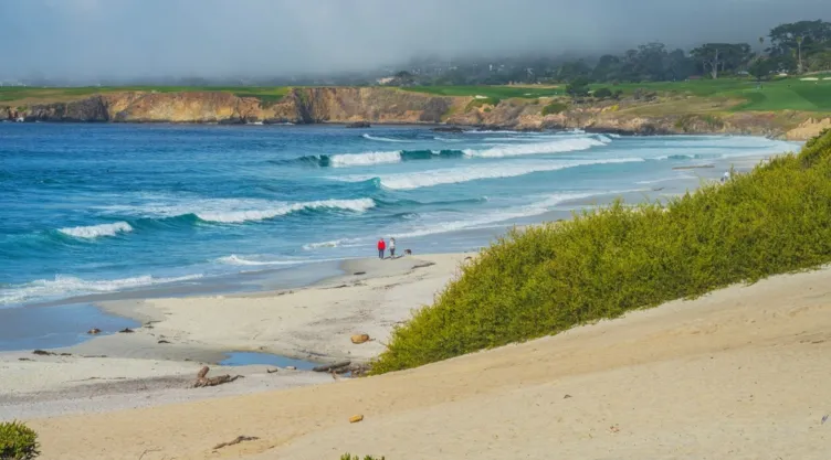 Unas personas caminan por la playa en Carmel, California.