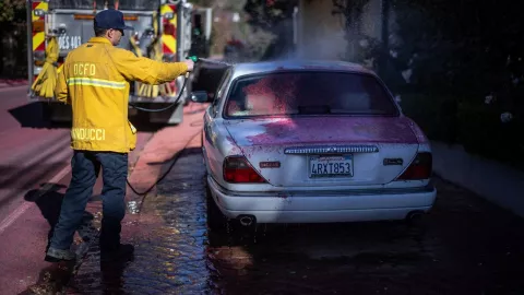 Bomberos de la ciudad de California limpian el Polvo rosa utilizado para combatir los incendios en Los Ángeles, que comienza a pintar los coches con su característica tonalidad.