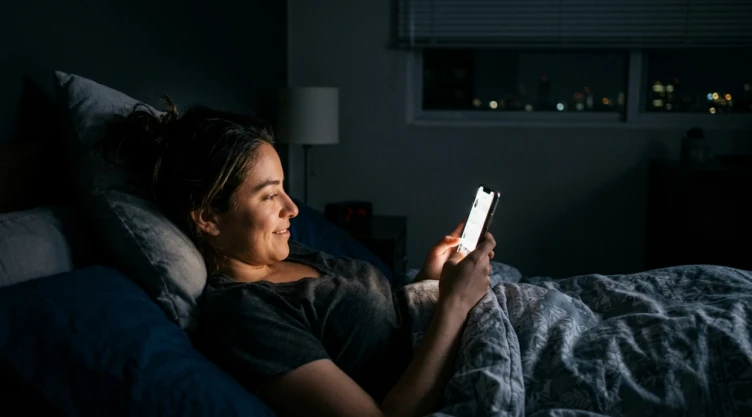 Mujer acostada viendo el celular antes de irse a dormir