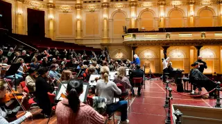 Las personas se cortan el cabello mientras toca una orquesta en vivo.