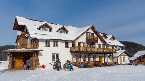 Un centro de esquí, con el edificio principal cubierto de nieve y los visitantes en el lugar