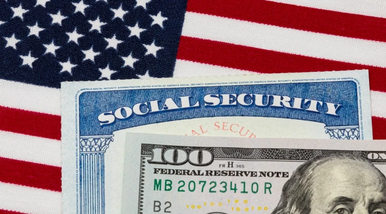 Cheque del Seguro Social junto a dólares y la bandera de EU