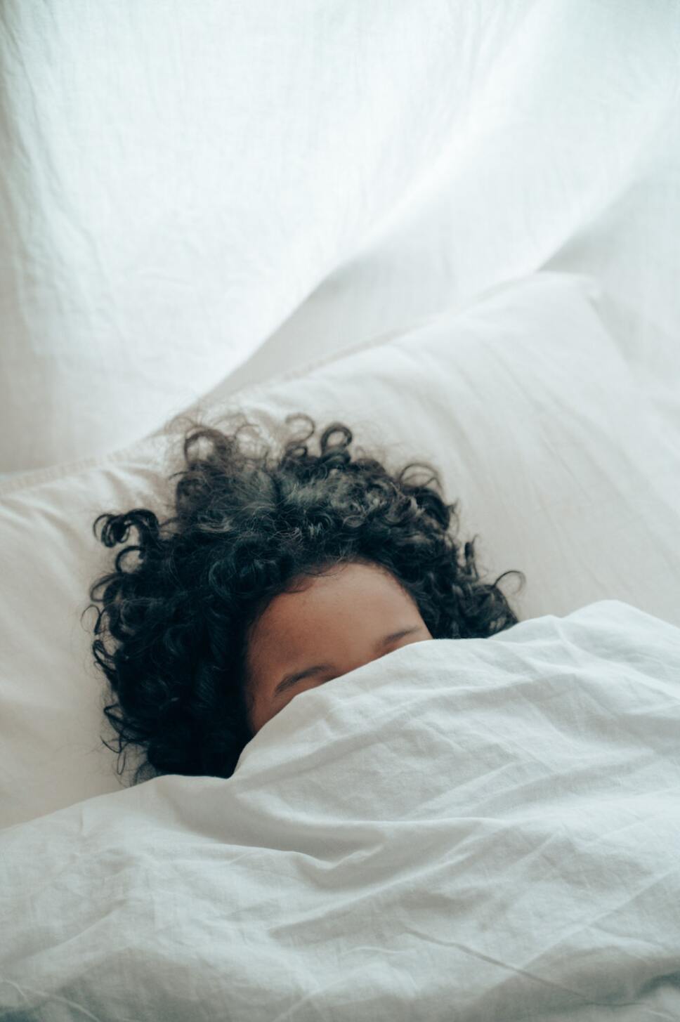 niño durmiendo sobre colchon y bajo las sabanas