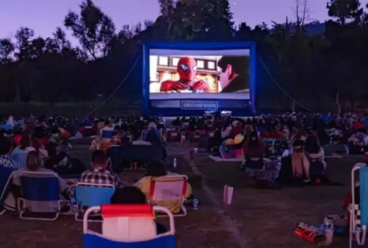 un grupo de cinéfilos reunidos a aire libre viendo Spider-Man.