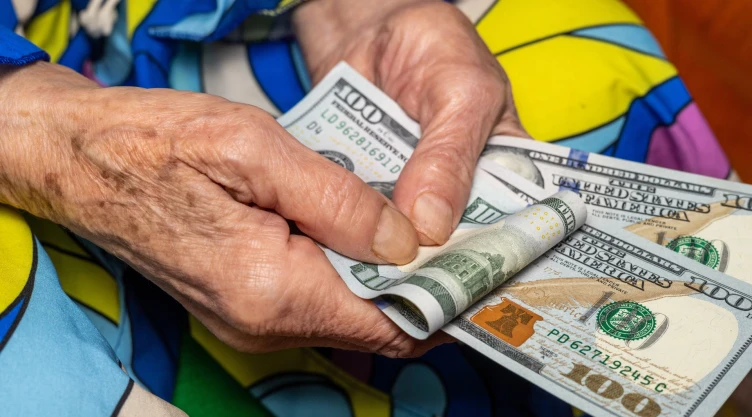 Una persona sostiene varios billetes de 100 dólares.