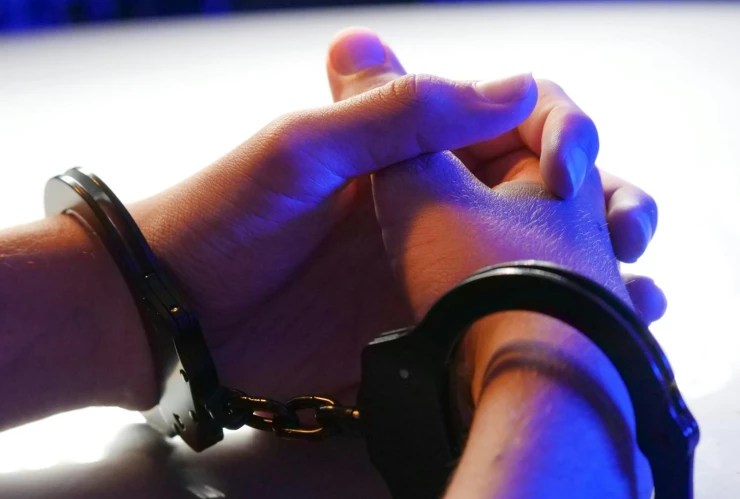 Manos entrelazadas con esposas en las muñecas