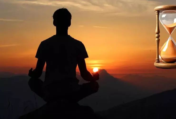 Persona meditando. Una puesta de sol de fondo y un reloj de arena
