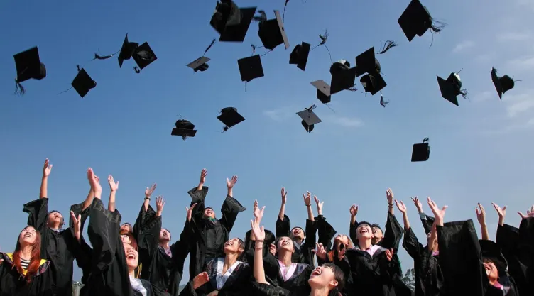 Estudiantes lanzando su sombrero de graduación