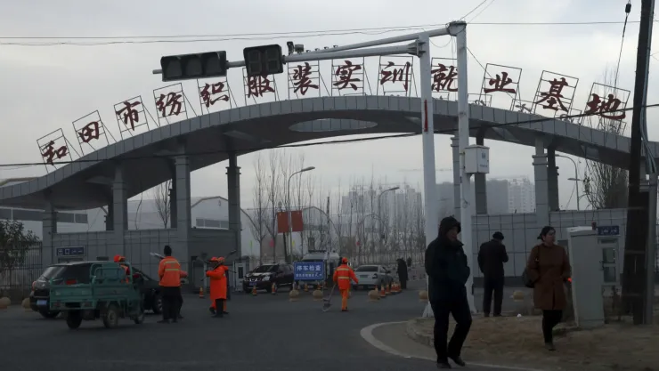 Unas personas caminando a la entrada de la ciudad de Hotan, donde la empresa Hetian Taida Apparel Co. tiene una planta, en el oeste de China, el 5 de diciembre de 2018. Imagen, AP.