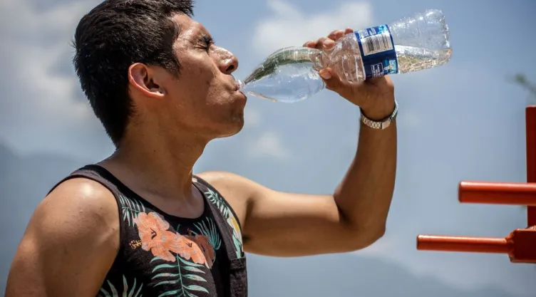 Un hombre tomando agua para refrescarse en medio de una ola de calor.