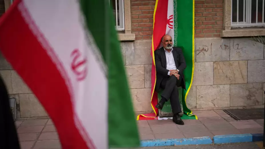 Un hombre junto a una bandera iraní en Teherán.