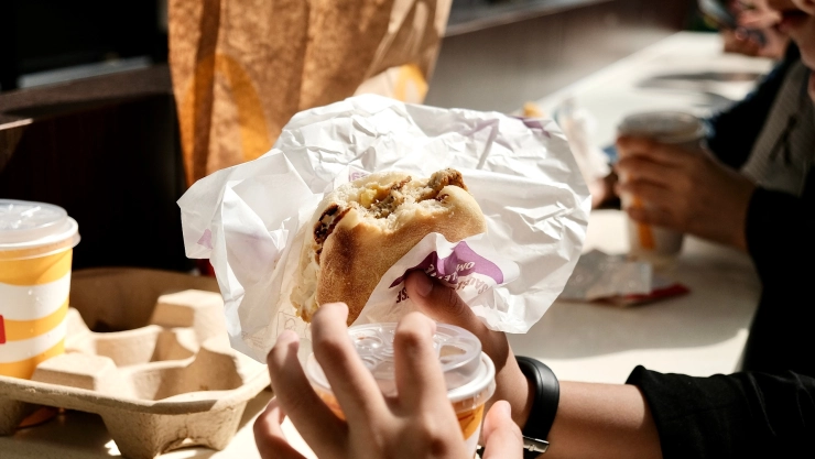 Un hombre come hamburguesa de Mc Donalds