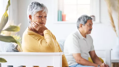 Una pareja de adultos mayores sentados en un sill&oacute;n.