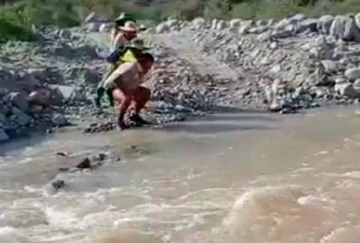 Maestro carga a alumnos para cruzar el río