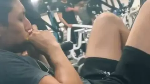 El joven que hace rutina de ejercicio en el gimnasio mientras come comida de PERRO
