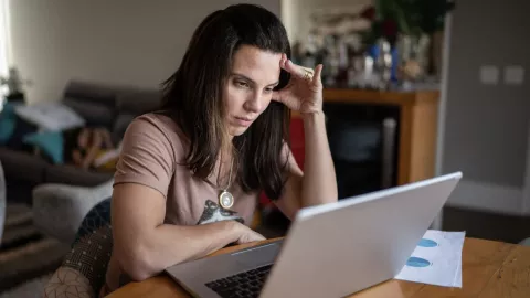 mujer frente a una computadora, visiblemente enojada o estresada