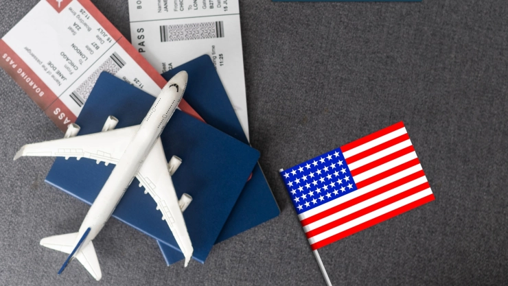 Un pasaporte junto a una bandera estadounidense y la maqueta de un avión