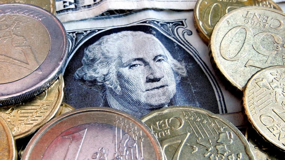 Monedas de euro y billetes de dólar.