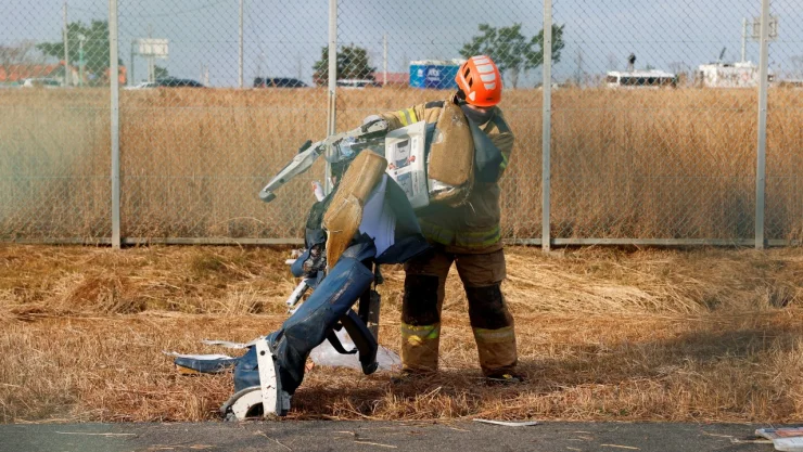 Bombero recoge restos del avión que sufrió un accidente en Corea del Sur.