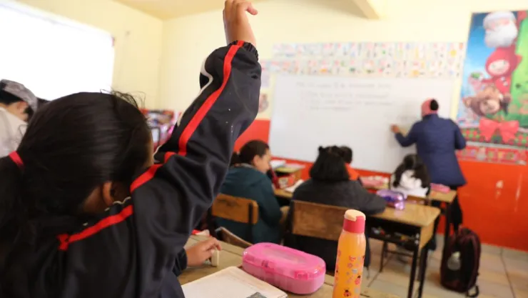 Alumna de educación levanta la mano para participar en clase.