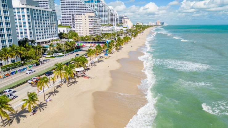 Vista aérea de las playas de Fort Lauderdale, con las aguas cristalinas, arena blanca, palmeras en la costa e imponentes edificios.