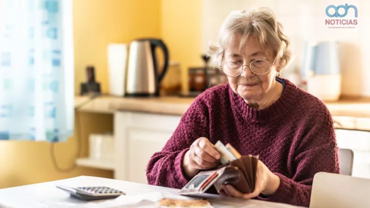 Una mujer mayor sacando billetes de su cartera.