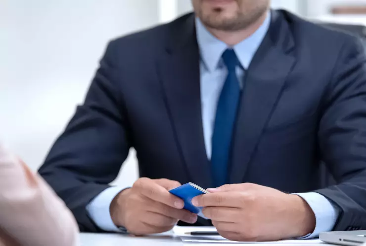 Un hombre sostiene un documento frente a una mesa con una bandera estadounidense