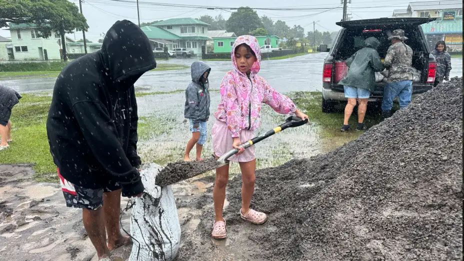 Una familia coloca sacos de arena ante la cercanía del huracán Nolo, en Hilo, Hawái.