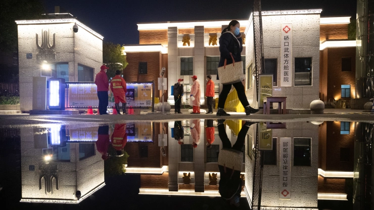 Workers wearing face masks are seen in front of a makeshift hospital that is closed following its last group of patients of the novel coronavirus have been discharged, in Wuhan