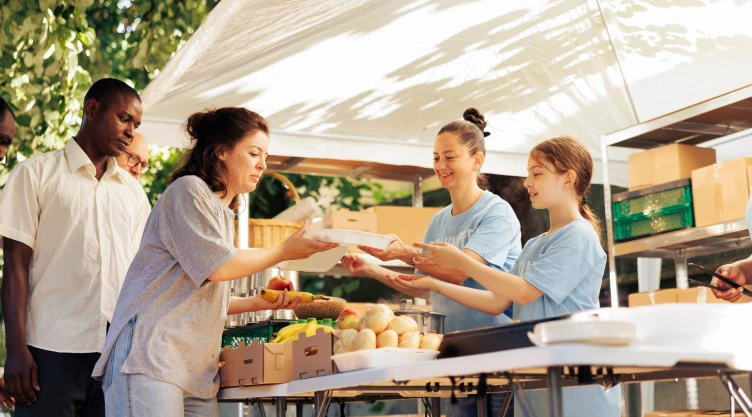 Dos mujeres le entregan alimentos a ciudadanos