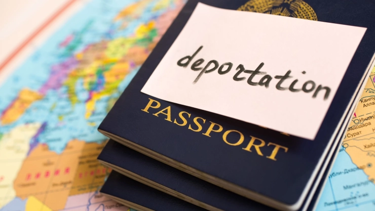 Un pasaporte con un cartel de deportación sobre un mapa.