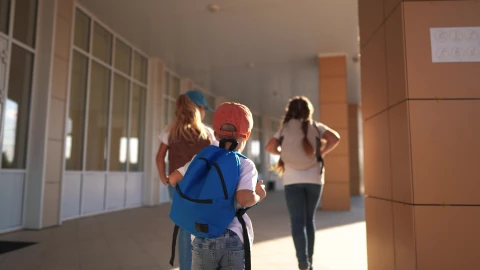 Niños corren por los pasillos de una escuela.
