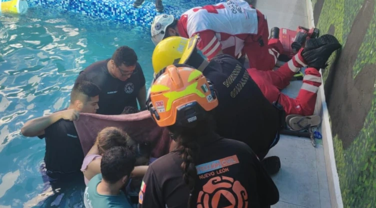 Rescatan a niña atrapada en tubería dentro de alberca en Guadalupe, NL. En la imagen se observa cómo elemento de Protección Civil, Bomberos y familiares tratan de rescatar a la menor atrapada.