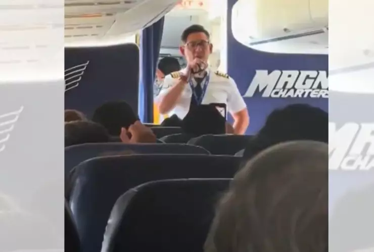 Piloto de la aerolínea Magnicharters habla con pasajeros dentro de la cabina de un avión en el AICM, durante un incidente que mantuvo el vuelo en tierra.