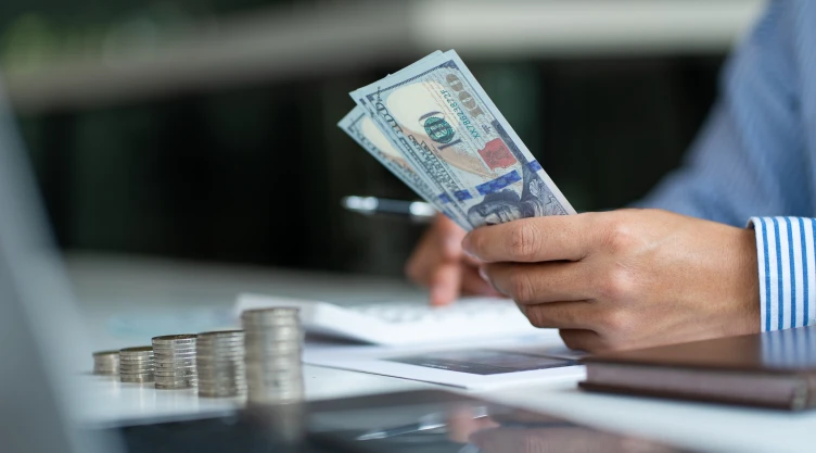 Una persona hace cálculos con dinero en dólares.
