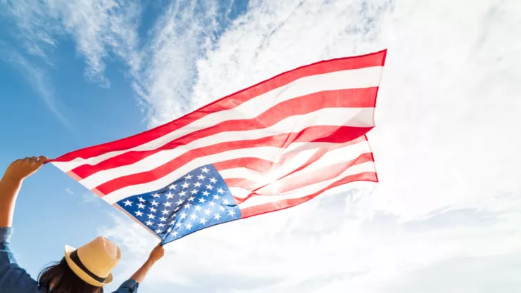 Una mujer ondea la bandera de Estados Unidos hacia el cielo