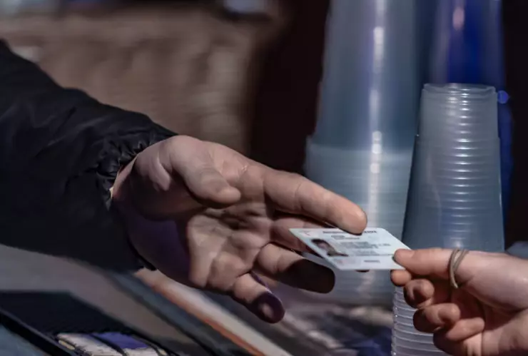 Una persona entrega su ID a una persona.