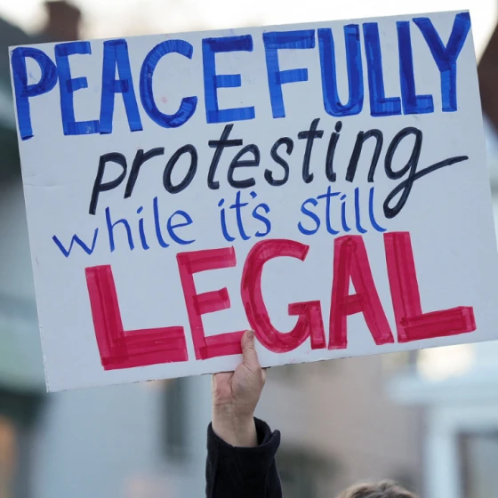 Una mujer sostiene un cartel durante una vigilia en memoria de una mujer de 37 años que recibió un disparo en su automóvil por parte de un agente de inmigración de Estados Unidos, según funcionarios locales y federales, en Minneapolis