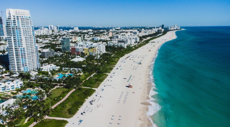 Ciudad costera de Florida desde una toma aérea, donde se aprecia el mar turquesa, la playa y los edificios