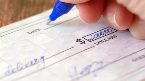 Una persona llena un cheque.