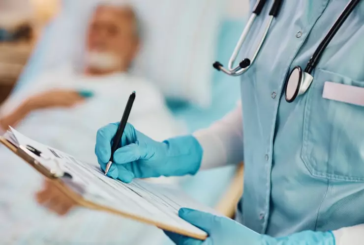 Un profesional de la salud rellena un formulario al lado de un paciente ingresado