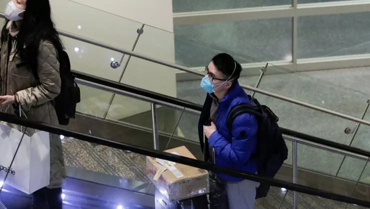 Travellers wearing masks arrive on a direct flight from China at Seattle-Tacoma International Airport