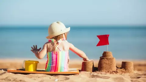 Una bebé juega feliz sobre la arena