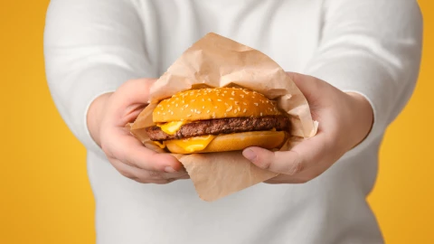 Una persona sostiene una hamburguesa con queso.