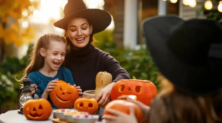 una madre y su niña decoran una calabaza