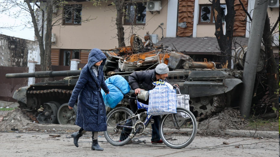 Civiles caminan frente a un tanque destrozado en Mariúpol, Ucrania.