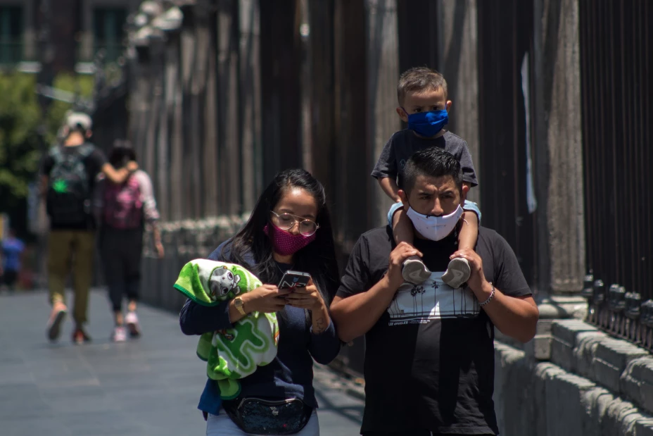 En medio de medidas sanitarias de la “nueva normalidad”, como lo es el uso de cubrebocas, una familia camina frente a la catedral de la Ciudad de México