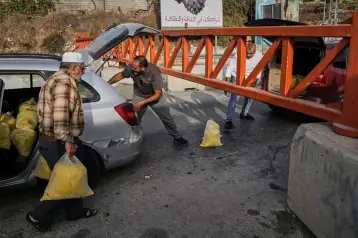 Palestinos frente a una barrera militar que cierra el paso en Hebrón, Cisjordania.