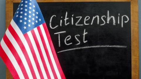 Una pizarra en la que se lee “examen de ciudadanía” junto a una bandera estadounidense.